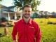 Dog poop pickup in a suburban backyard with a technician and a playful dog.