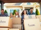 Family enjoying house moves with boxes in front of their new home, radiating joy.
