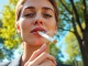 Man exhaling from nicotine free cigarettes in a lush park, promoting a healthier lifestyle.