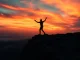 Fight or flight moment captured as a figure stands on a cliff amidst a dramatic sunset.