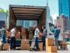 Dynamic view of a Manhattan moving company team loading boxes into a van in a vibrant urban setting.